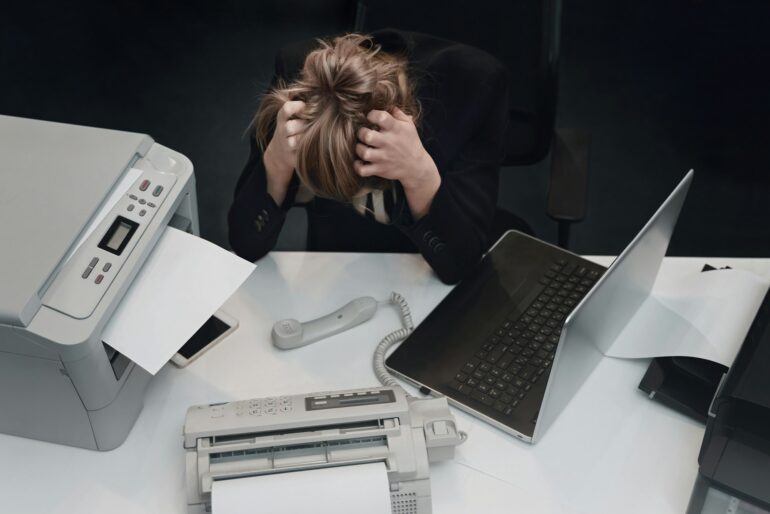 Stressed tired businesswoman feels exhausted sitting at office desk with laptop