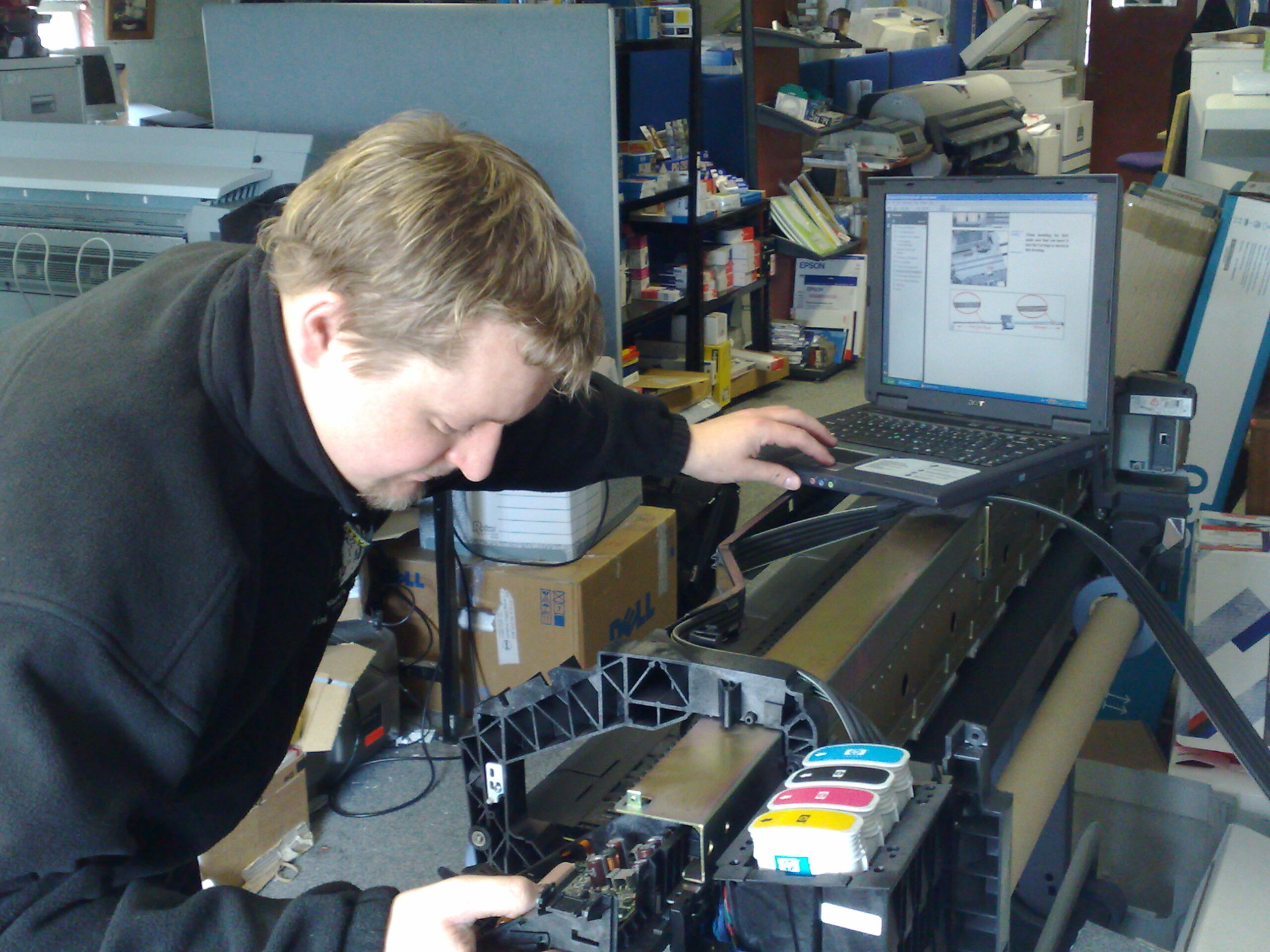 Una persona reparando un plotter de impresión